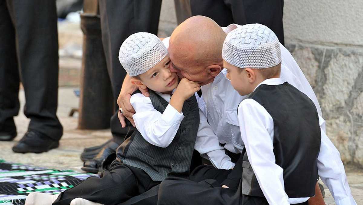 بوسني يقبل أطفاله خلال انتظار أداء صلاة العيد