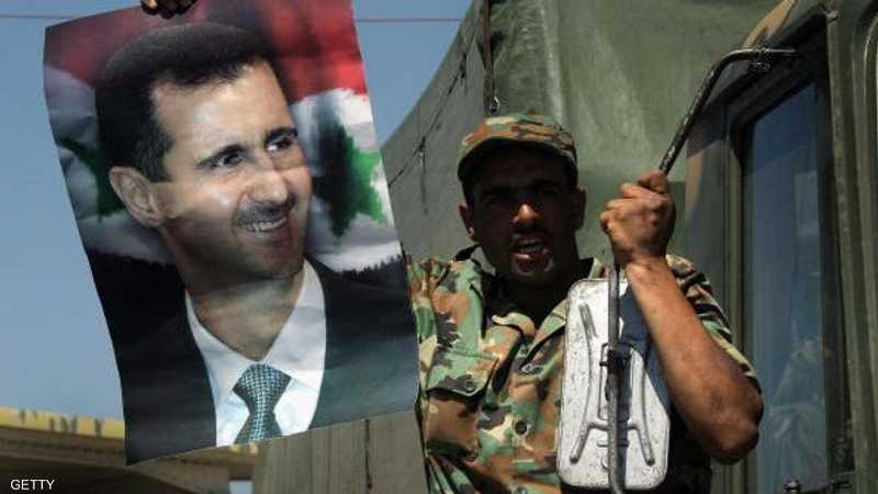 جندي سوري يرفع صورة الأسد.
