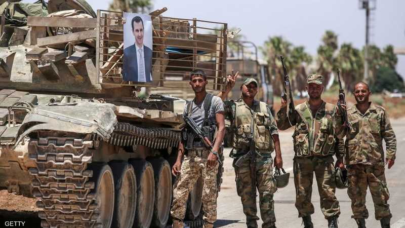 جنود امام دبابة تحمل صورة الأسد.