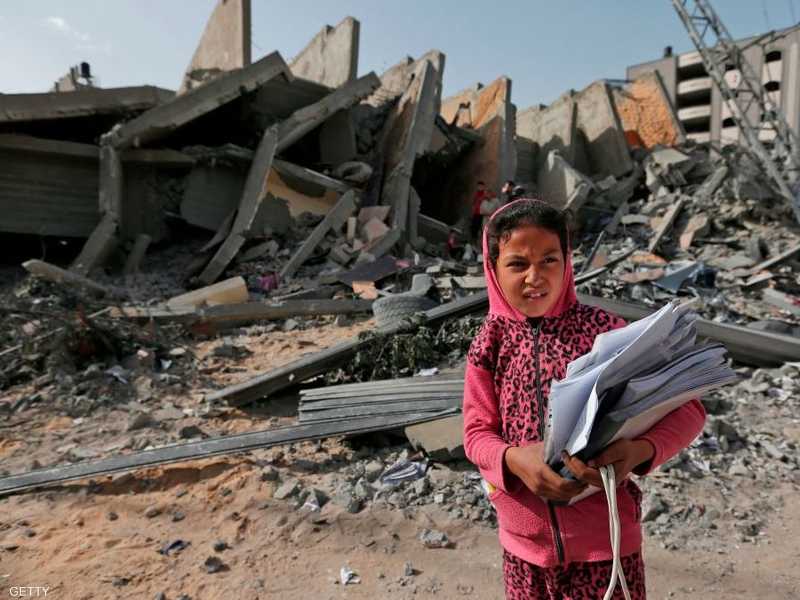 طفلة فلسطينية تقف أمام ركام مبنى دمرته الغارات الإسرائيلية